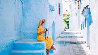 A woman in a yellow dress enjoys a peaceful moment in a bright, airy space with blue accents | MSC Cruises