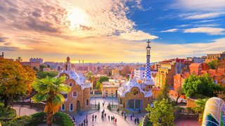 A panoramic view of a vibrant cityscape with water and trees, under a bright sky at sunset | MSC Cruises