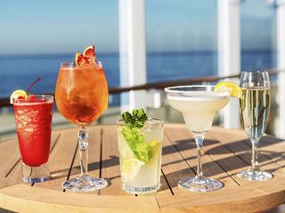 A selection of refreshing cocktails and drinks arranged on a table by the sea, perfect for enjoying on board | MSC Cruises