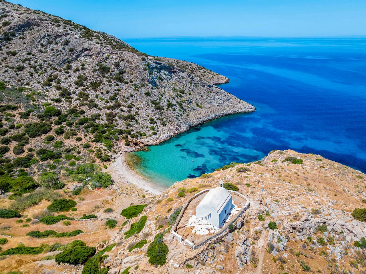 Stunning coastal view of Syros Island in Greece, featuring clear blue-green waters and rocky hills | MSC Cruises