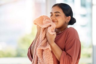 A woman smiles while hugging a blanket, enjoying a cozy moment | MSC Cruises