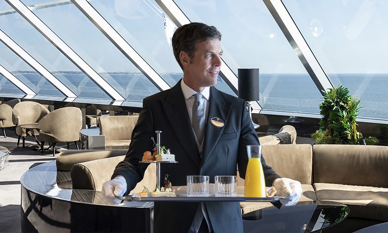 A waiter serves a drink in an elegant restaurant with a sea view | MSC Cruises