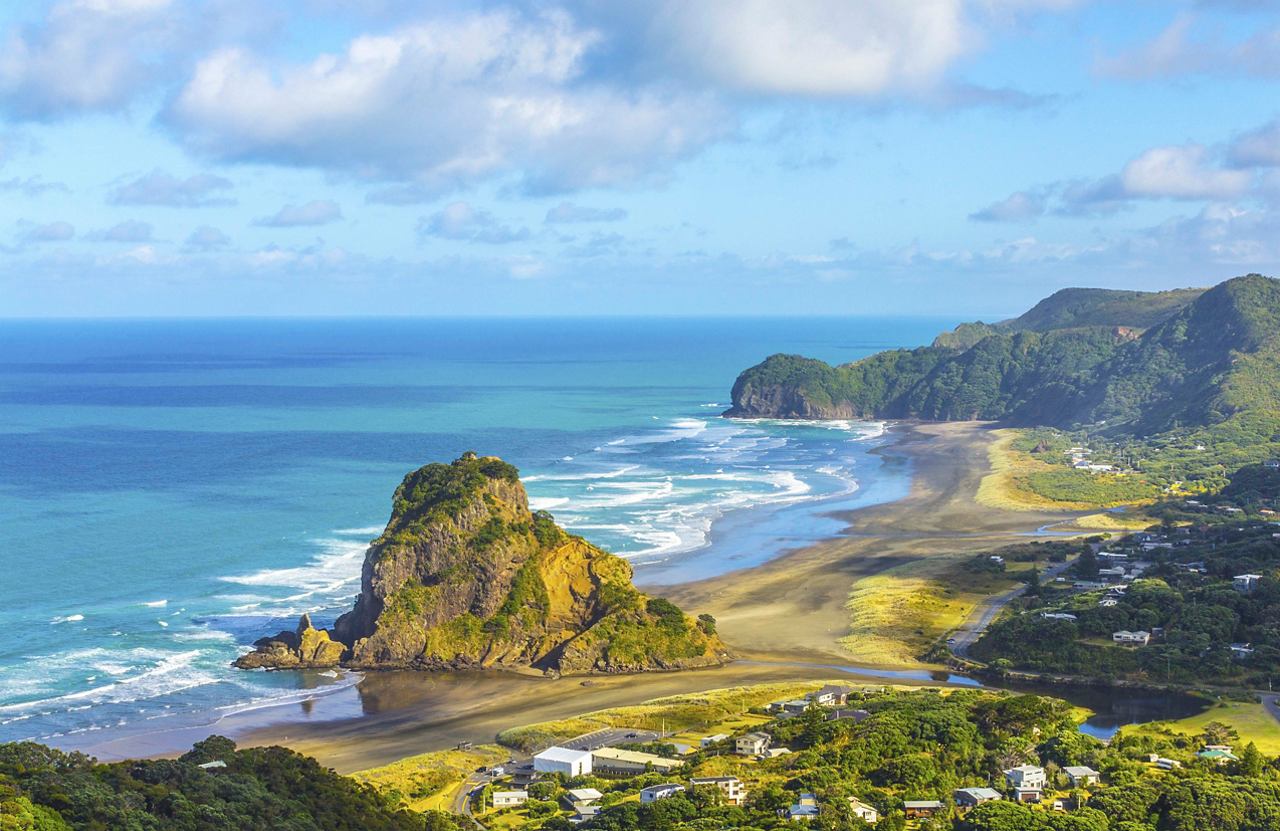 A stunning coastal view of Lion Rock at Piha Beach, showcasing lush vegetation and the vibrant sea | MSC Cruises