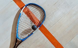 A squash racket resting on the court floor, highlighting the vibrant orange line | MSC Cruises