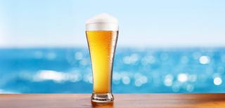 A glass of beer set against the ocean and blue sky | MSC Cruises