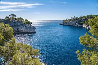 Mer bleue tranquille entourée de côtes rocheuses et de verdure luxuriante | MSC Croisières
