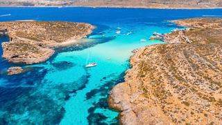 Aerial view of coastline and boat in the blue Mediterranean Sea near Malta | MSC Cruises