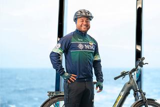 Happy bike tour leader smiling in front of MSC Euribia cruise ship | MSC Cruises