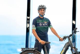 A bike tour leader stands with a bicycle on MSC Euribia overlooking the sea | MSC Cruises