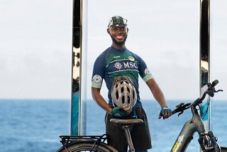 Smiling bike tour leader near MSC Euribia ship under clear blue sky | MSC Cruises