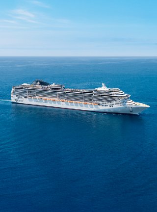 A majestic cruise ship gliding through tranquil blue waters under a clear sky | MSC Cruises