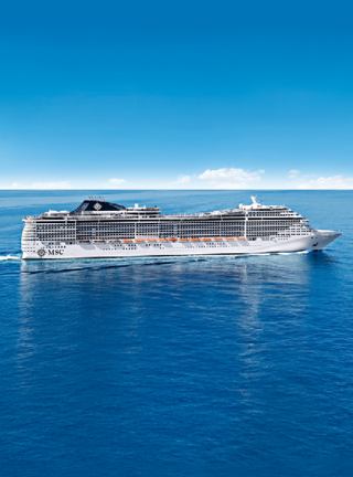 Ein prächtiges Kreuzfahrtschiff gleitet über ruhiges blaues Wasser unter einem klaren Himmel | MSC Cruises