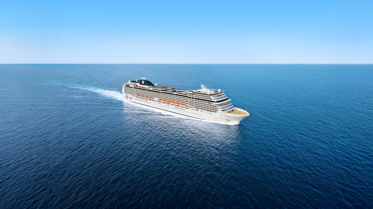 A majestic cruise ship gliding through calm blue waters under a clear sky | MSC Cruises