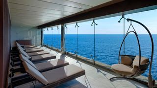 Sitting area with sunbeds and a hanging chair overlooking the sea | MSC Cruises