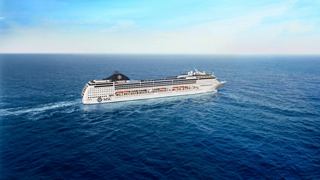 Ein majestätisches Kreuzfahrtschiff gleitet durch ruhige blaue Gewässer unter einem klaren Himmel | MSC Cruises