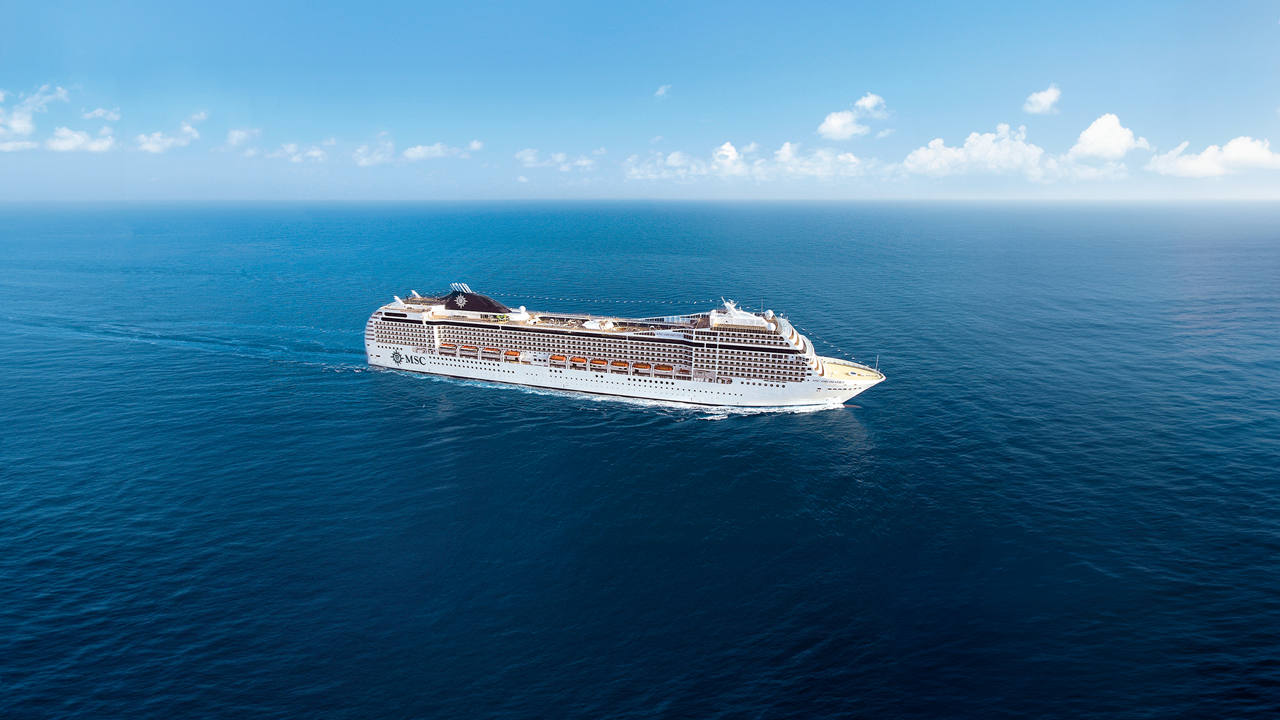 A majestic cruise ship gliding smoothly across the tranquil blue sea under a clear sky | MSC Cruises