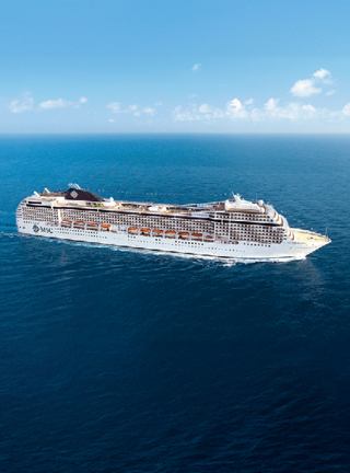 Ein majestätisches Kreuzfahrtschiff segelt durch klares, blaues Wasser unter einem hellen Himmel | MSC Cruises