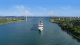 A ship sails through the Panama Canal, surrounded by greenery and blue skies | MSC Cruises