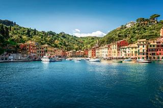 A serene view of Portofino's vibrant waterfront, surrounded by lush hills and charming buildings | MSC Cruises