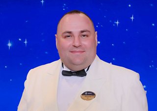 Captain in a white uniform smiling against a blue background | MSC Cruises