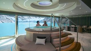 Zwei Personen entspannen im Whirlpool mit Blick auf das Meer durch große Fenster | MSC Cruises