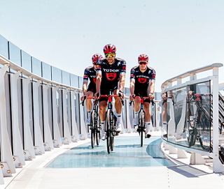 Three individuals in matching uniforms confidently walk along a modern walkway on a cruise ship | MSC Cruises