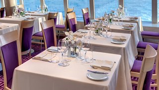 Elegant dining area with white tablecloths and purple chairs | MSC Cruises