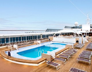 A spacious pool area on a cruise ship deck with sun loungers and a clear blue sky in the background | MSC Cruises