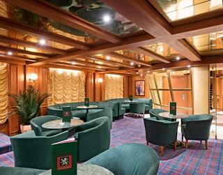 Gemütliche Atmosphäre in der Bar The White Lion mit grünen Stühlen und warmem Licht | MSC Cruises