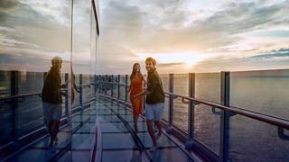 Una coppia cammina sul ponte Infinity di MSC Seashore al tramonto in autunno | MSC Cruises