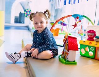 A young child plays on the floor surrounded by colourful toys in a bright, playful environment | MSC Cruises