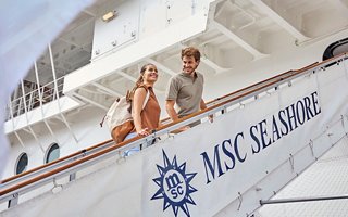 Una pareja sonríe en la cubierta del barco, disfrutando de un día soleado | MSC Cruceros