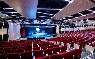 Espacio teatral moderno con asientos rojos y escenario, listo para una actuación | MSC Cruceros