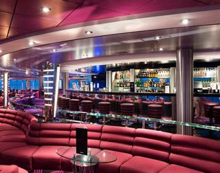 A vibrant lounge area with plush seating and a sleek bar, inviting guests to relax and enjoy the evening | MSC Cruises