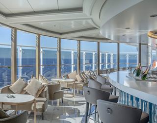 Un elegante bar de champán con vistas panorámicas al mar y arreglos de asientos elegantes | MSC Cruceros