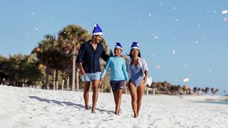 Eine Familie genießt einen sonnigen Tag am Strand, trägt Hüte und lächelt | MSC Cruises