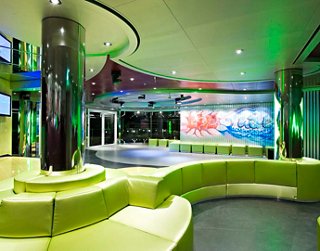 A vibrant lounge area on MSC Splendida featuring green seating and a dynamic atmosphere for entertainment and dancing | MSC Cruises