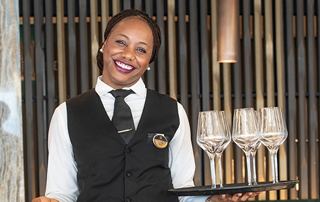 A smiling server offers drinks to guests in an elegant setting | MSC Cruises