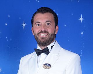 Crew member in white uniform with a formal name tag and smile | MSC Cruises