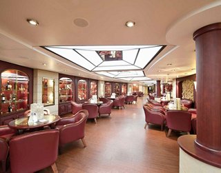 A spacious and elegant wine bar featuring plush armchairs and tables, perfect for enjoying fine wines | MSC Cruises