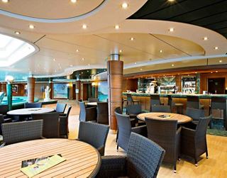 A spacious and inviting bar area with tables and chairs for relaxation near the pool on MSC Splendida | MSC Cruises