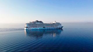 Un majestueux paquebot glisse sereinement sur des eaux calmes, reflétant le ciel clair | MSC Croisières