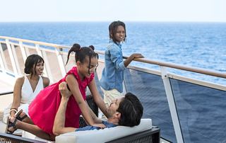A family enjoys quality time together on a cruise, with a beautiful ocean view in the background | MSC Cruises
