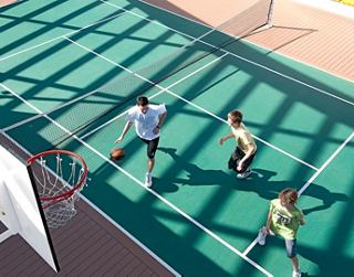 Guests enjoying a game of basketball on a spacious outdoor court, surrounded by vibrant greenery | MSC Cruises