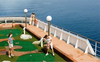Guests enjoy a game of mini-golf with stunning ocean views on a cruise ship deck | MSC Cruises