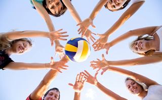 Un groupe d'amis tend les bras joyeusement pour attraper un volley-ball sous un ciel ensoleillé | MSC Cruises