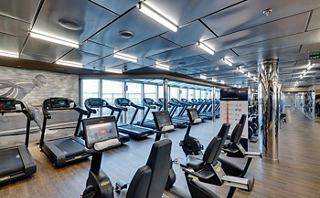 A spacious fitness area with modern equipment and ample natural light for an energising workout experience | MSC Cruises