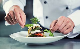 Un chef garnit un plat magnifiquement présenté sur une assiette blanche | MSC Cruises