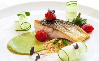 Gourmet fish dish presented with vegetables and sauces | MSC Cruises
