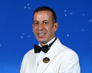 Crew member in white formal uniform with a bow tie | MSC Cruises